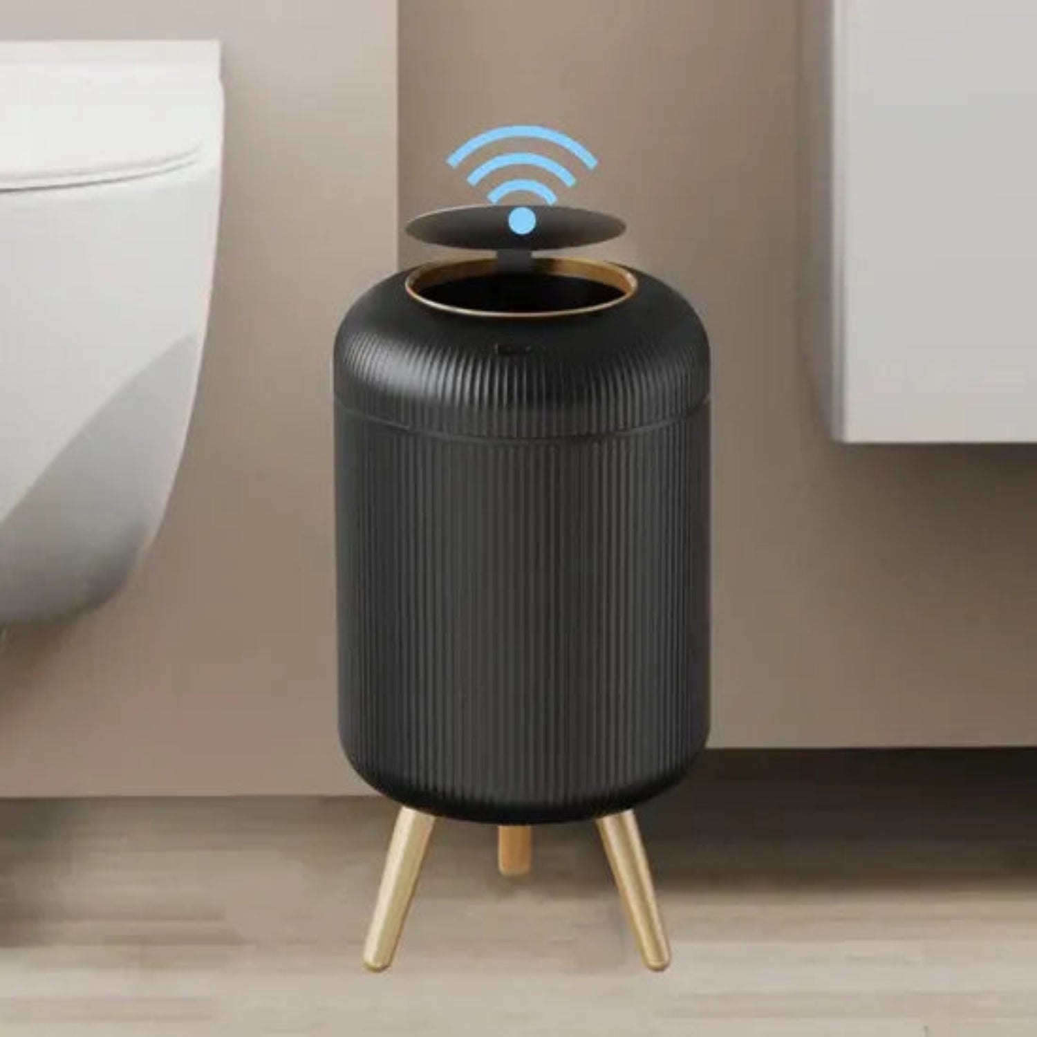 Black cylindrical device with gold legs on a wooden floor against a beige wall.