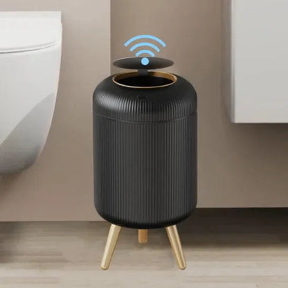 Black cylindrical device with gold legs on a wooden floor against a beige wall.